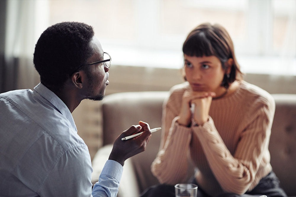 Young woman receiving advice on her dual diagnosis from therapist with glasses