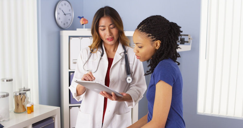 Doctor with clipboard explaining results to young woman in doctor's office