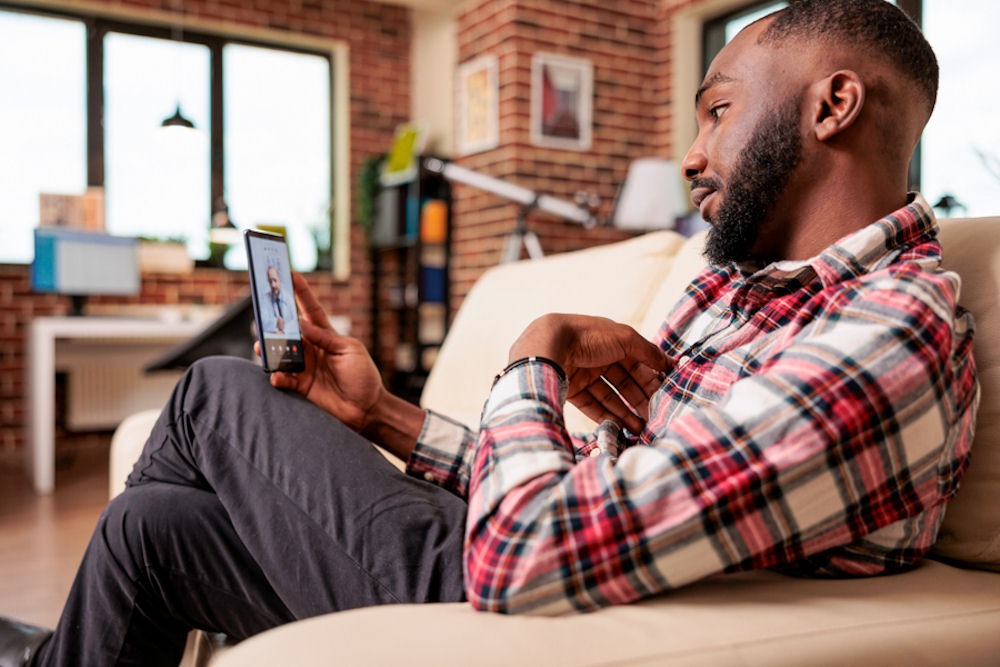 Man in flannel shirt video chats with doctor from phone