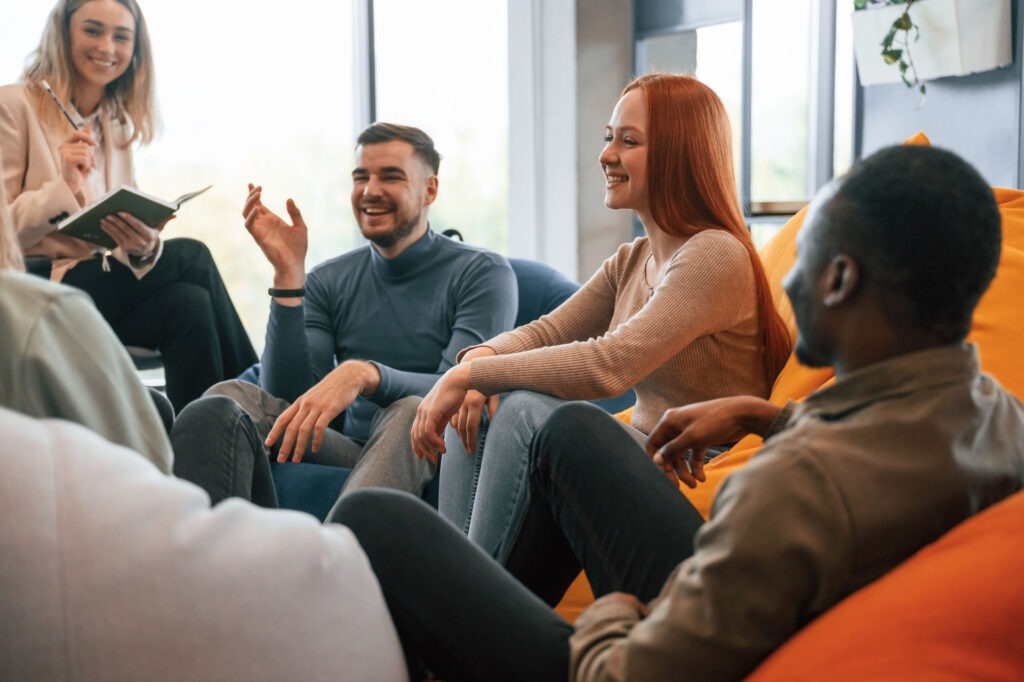 Sobriety support group of laughing people in bright room with natural lighting