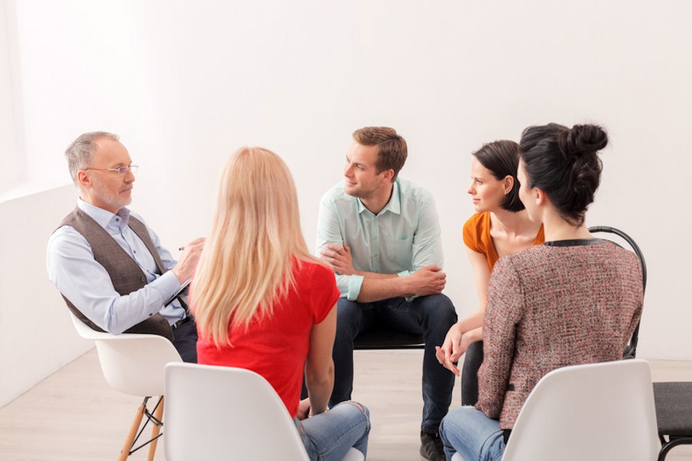 Individuals listening to therapist in codependency support group