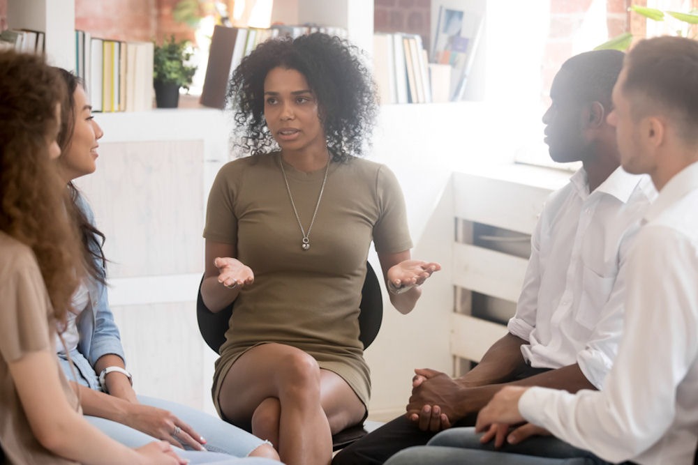 Woman discussing urges and cravings within addiction recovery group