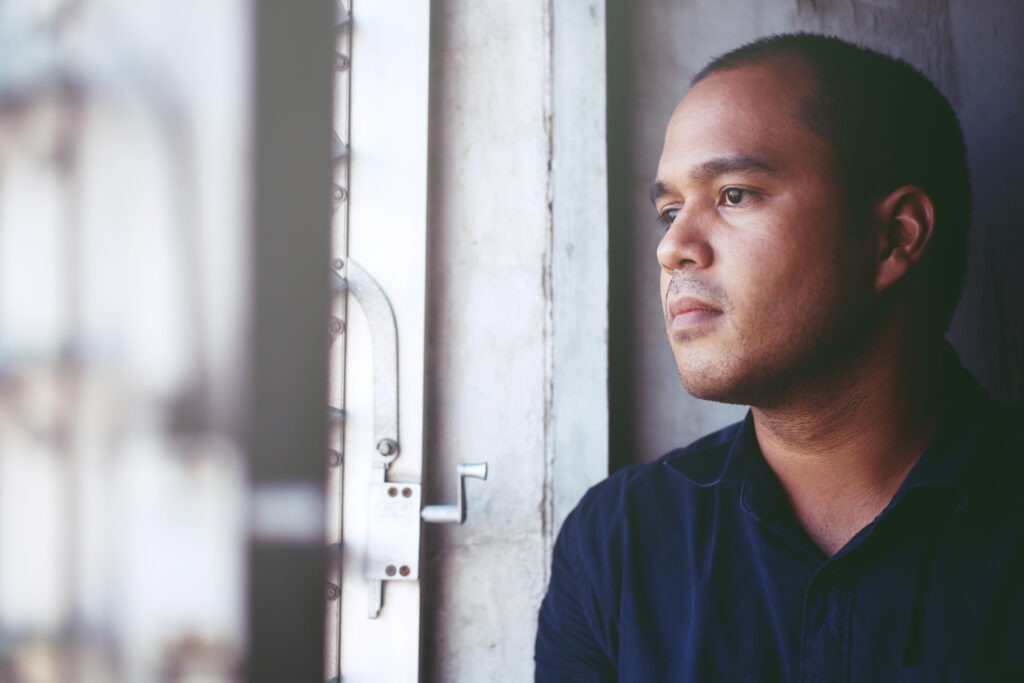 Man contemplating mental health while looking out the window at work