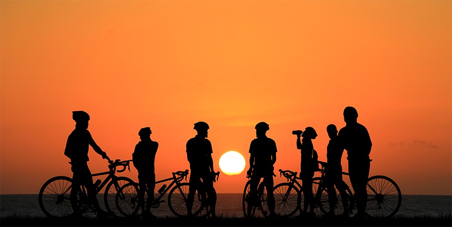 Group of bike riders resting against the backdrop of an orange sunset