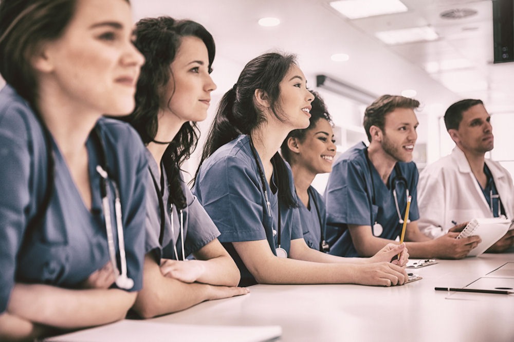 Group of doctors in grey scrubs at table learning about alcohol and vasoconstriction