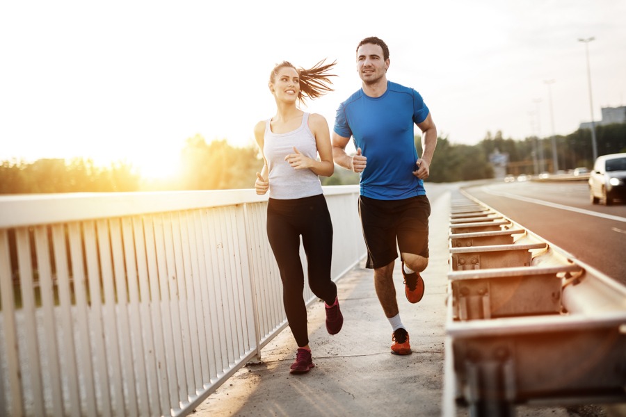 Woman and man running together on bridge