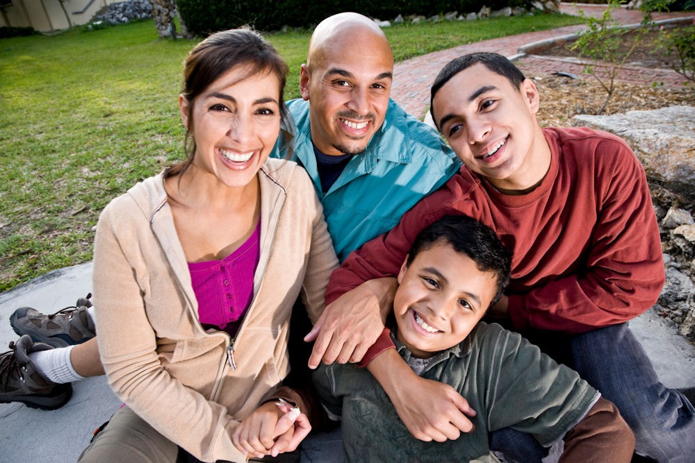 Happy family with heterosexual couple and two sons in a garden after a family program for addiction