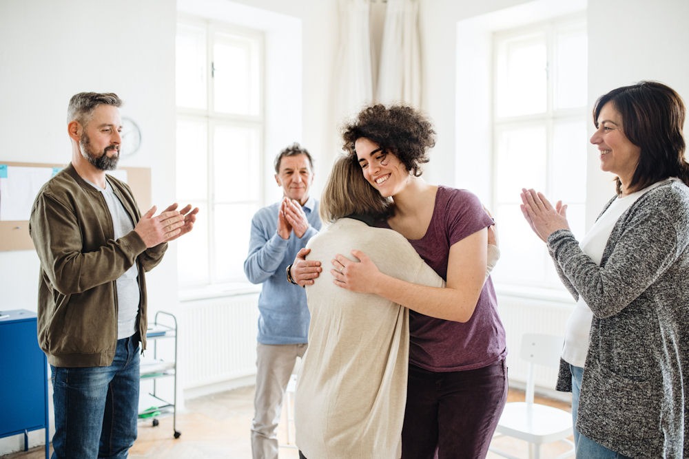 Woman embracing older woman in bipolar disorder and addiction support group