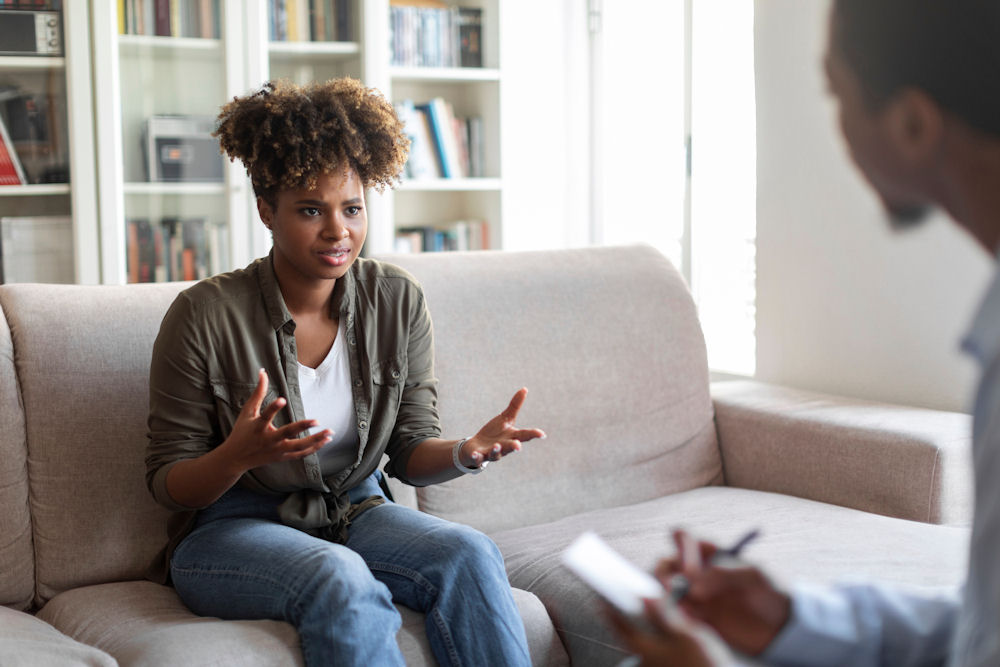 woman in therapy sitting on a couch talking to a therapist