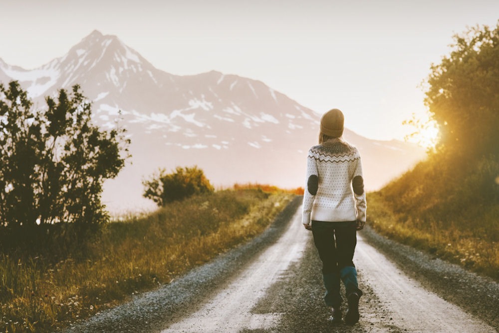 Woman on sunny winter road walking to help seasonal affective disorder