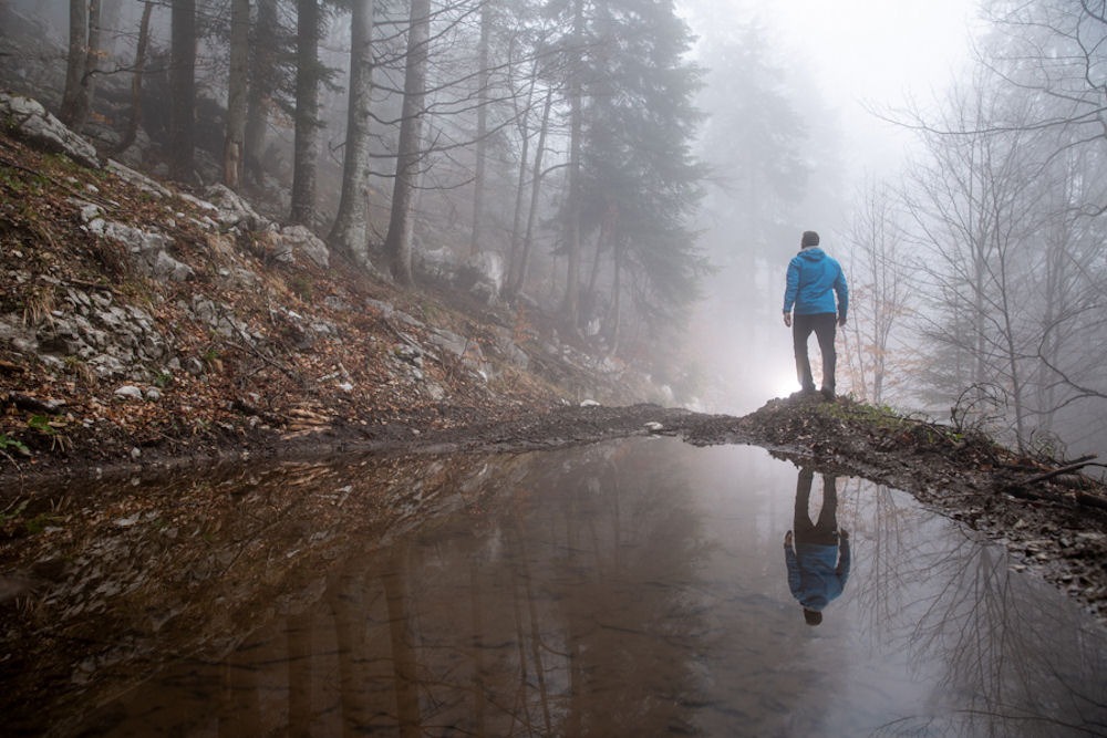 Man pausing while on a run in foggy forest