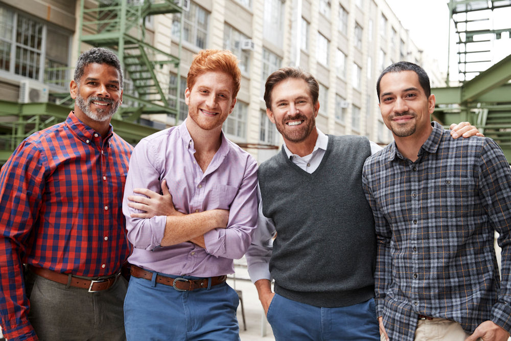 Group of four adult men hanging out in a city setting