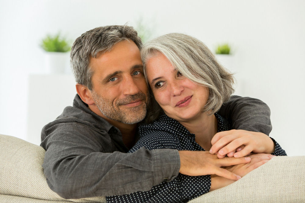 Smiling man hugging depressed partner.
