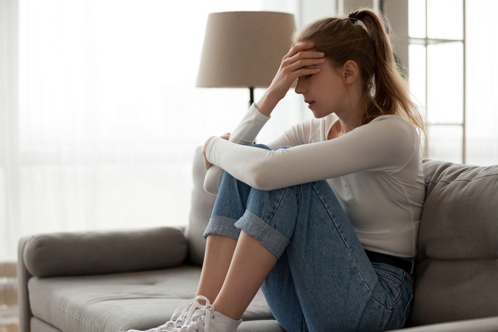 Frustrated woman holding forehead while writing moral inventory