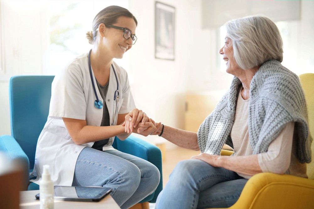 Doctor in white coat grasping an older woman's hand with two hands