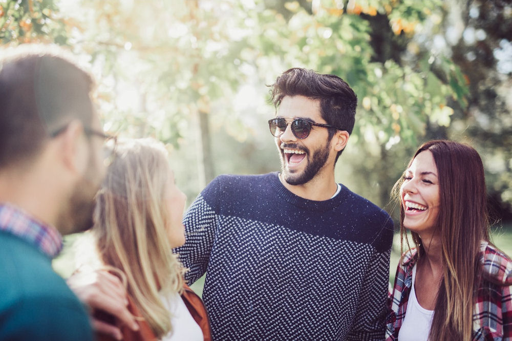Mixed-gender group of friends laughing while hanging out outside