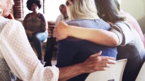 Women giving side hugs at a bipolar support group.