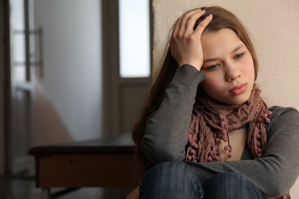 Woman with scarf holding head when contemplating making amends in recovery
