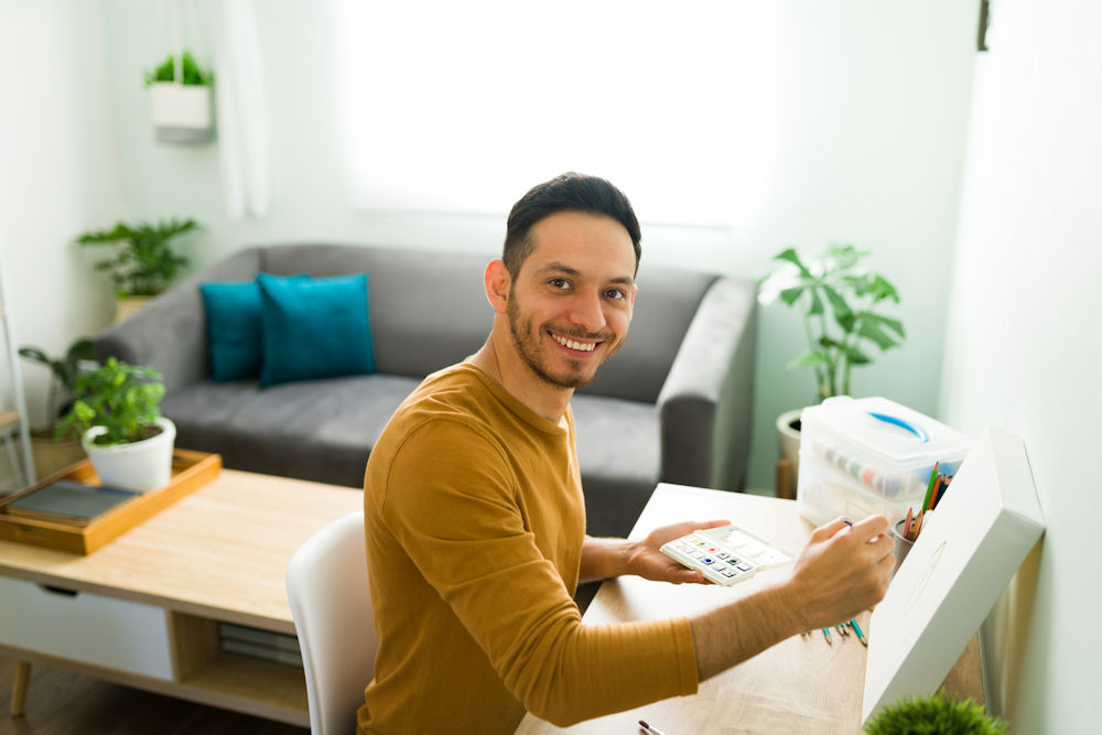 Man looks up from desk while completing art therapy for unemployment depression.