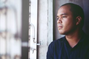 Man looking out the window after interacting with someone with alcohol-induced psychosis.