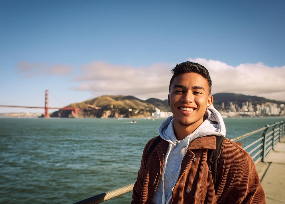 Happy young man posing on dock while traveling in San Francisco.