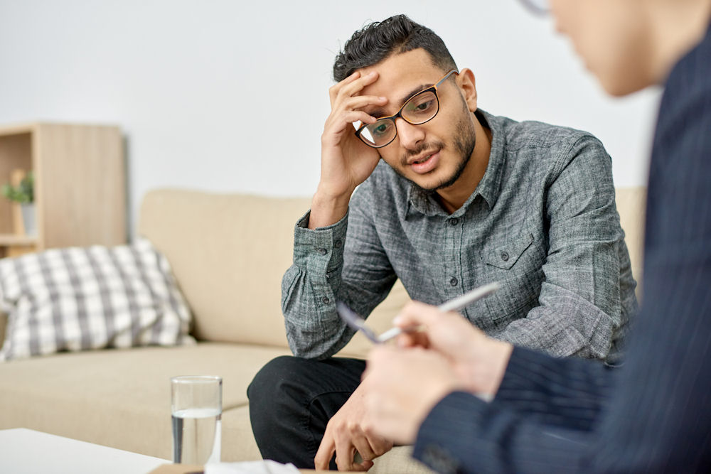 Frustrated man hearing recommendations from therapist with pad.