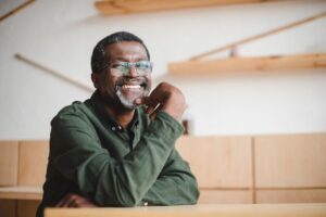 Professor with glasses smiling while sitting in a classroom.