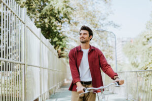 Man walking bicycle beside addiction recovery center.