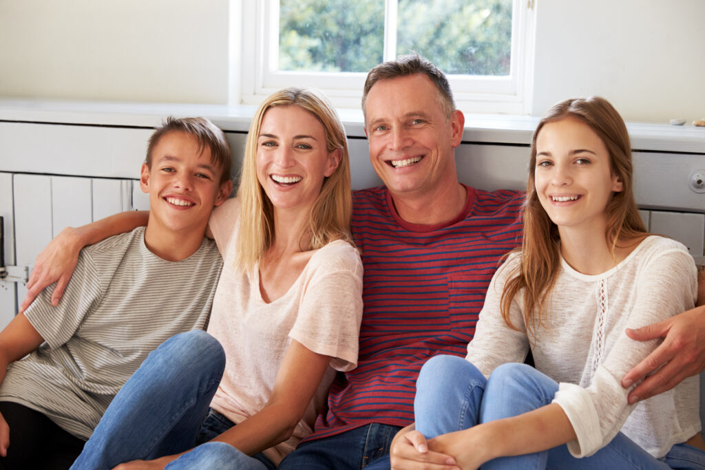 Family with straight couple and two children sitting on couch.