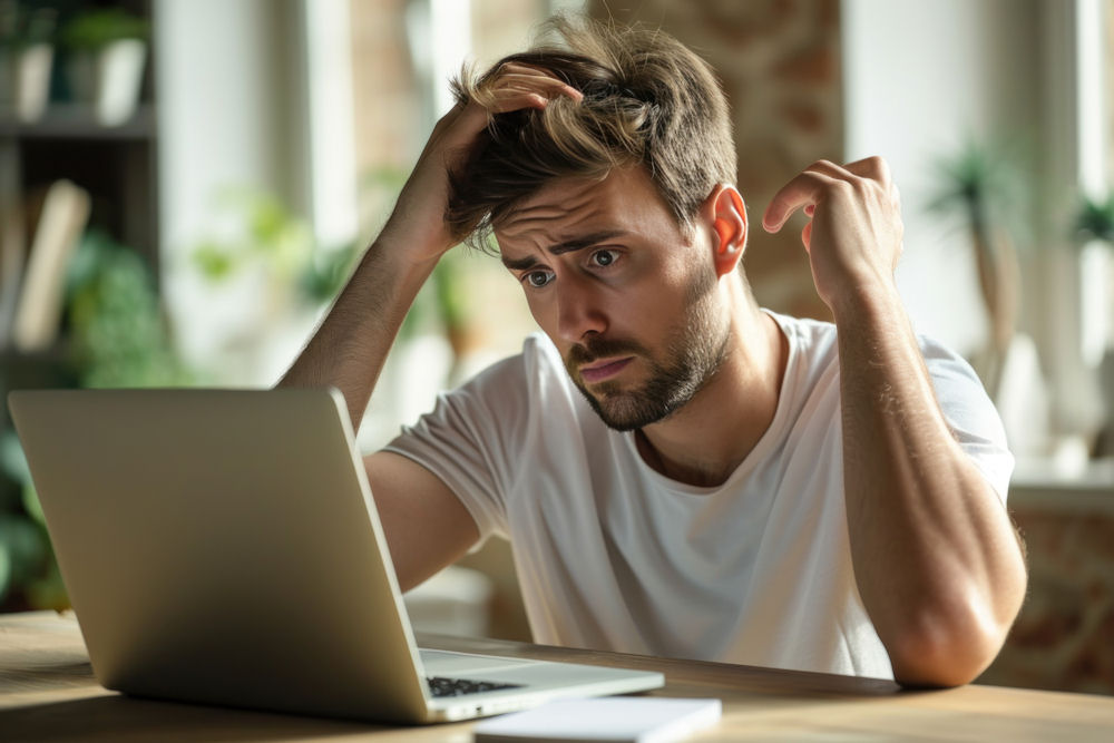 Frustrated man researching captagon on laptop.