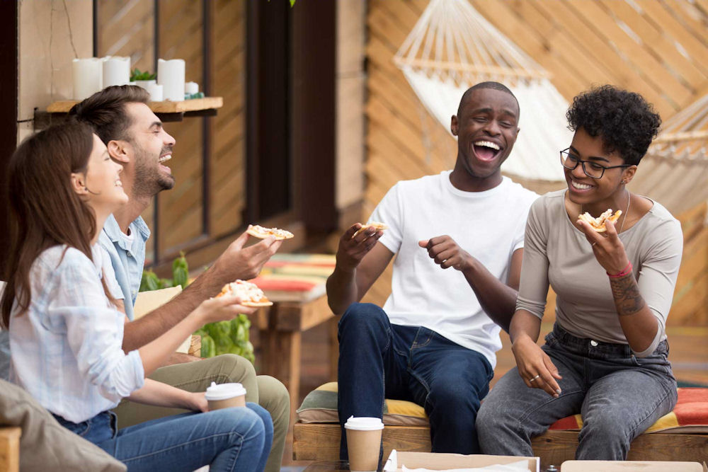 Group of people laughing at joke while eating pizza in Clovis, California.